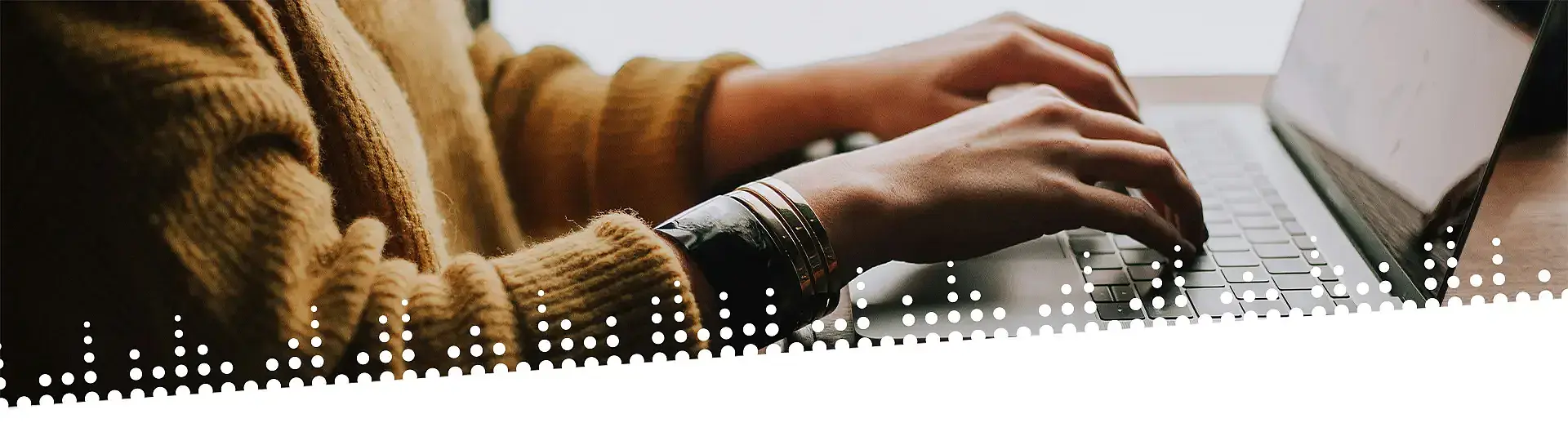 Frau mit gelbem Pullover tippt auf einer Laptoptastatur