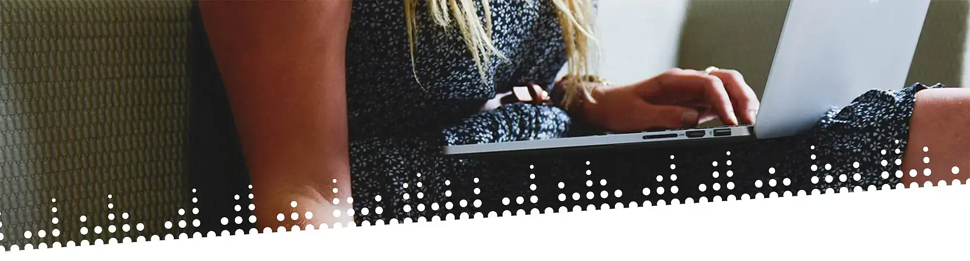 Frau sitzt auf dem Sofa und tippt mit einer Hand auf einer Laptoptastatur