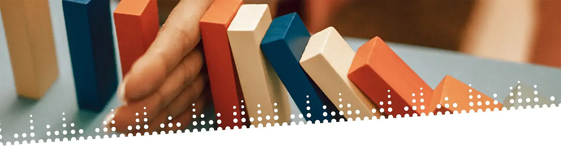 Hand hält fallende farbige Dominosteine auf